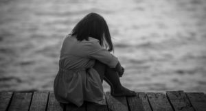 woman sitting on a dock in sadness and regret