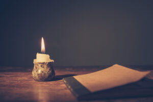 A dark, quiet room with a burning candle and a notebook on a table