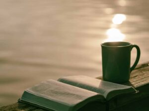 A bible and a coffee cup by the lakeshore