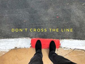 feet standing in front of a don't cross the line message