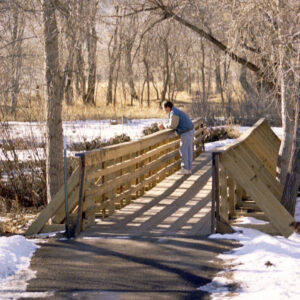 A man looking out into nature from a bridge