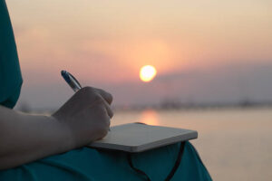 A woman writing her her journal at sunset