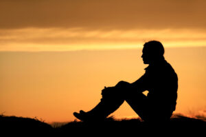 a person sitting in the sunset in prayer