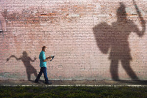 a shadow of David and Goliath behind a man reading his Bible