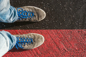 a pair of tennis shoes, one on a dark line, the other on a red line